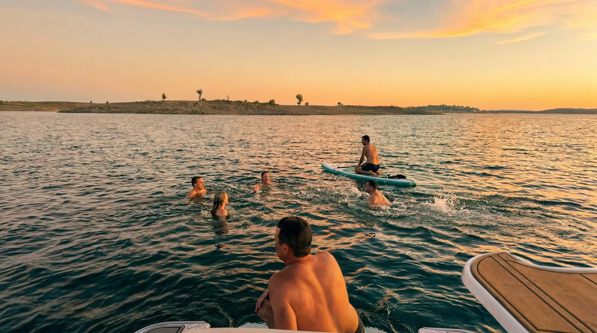 Swimmers and paddleboarders on Folsom Lake at sunset